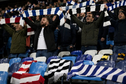 fans holding soccer scarves in stadium stands