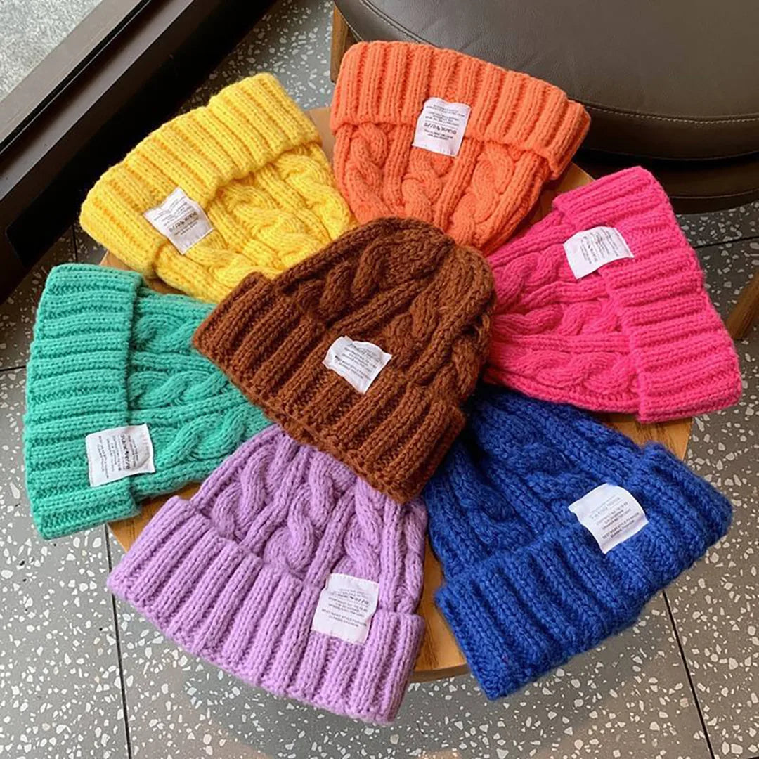 assorted cable pattern cuffed beanies in bright colors displayed on table