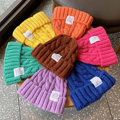 assorted cable pattern cuffed beanies in bright colors displayed on table