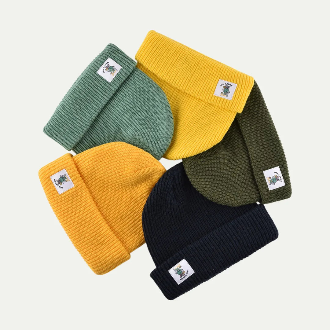 four solid color cuffed knit beanies arranged together in green yellow navy and orange